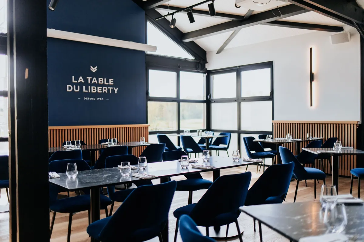 Salle de restaurant moderne et élégante, La Table du Liberty, avec des chaises bleues et des tables dressées à Paris.