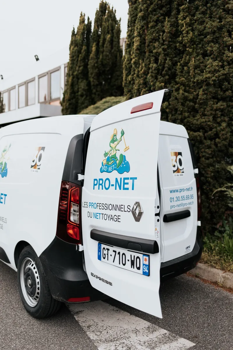 Véhicule de Pro-Net avec les portes arrière ouvertes, affichant le logo et les coordonnées de l'entreprise